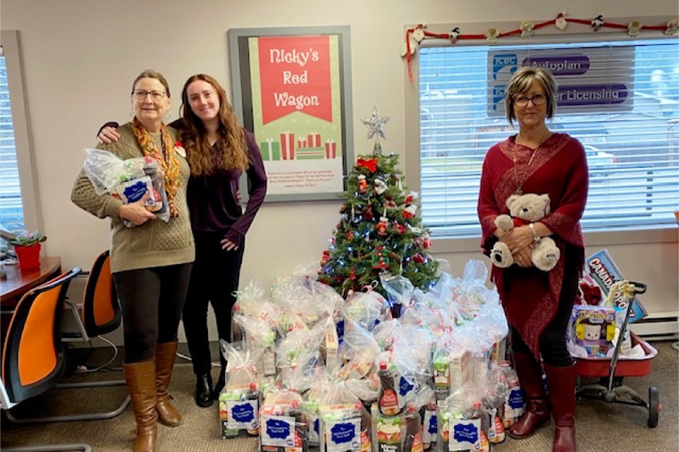 On Friday Dec. 13 (From L - R): Holly Fenrick (Interior Savings Insurance Branch Manager), Amanda Enham and Michelle Young amidst the large donations collected for Nicky's Red Wagon Campaign at Interior Savings in Barriere. 