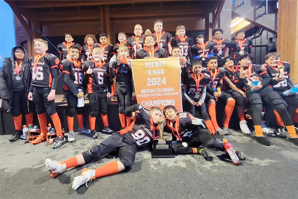 Cloverdale's Peewee Bobcats celebrate their provincial championship win with their banner, gold medals, and trophy.