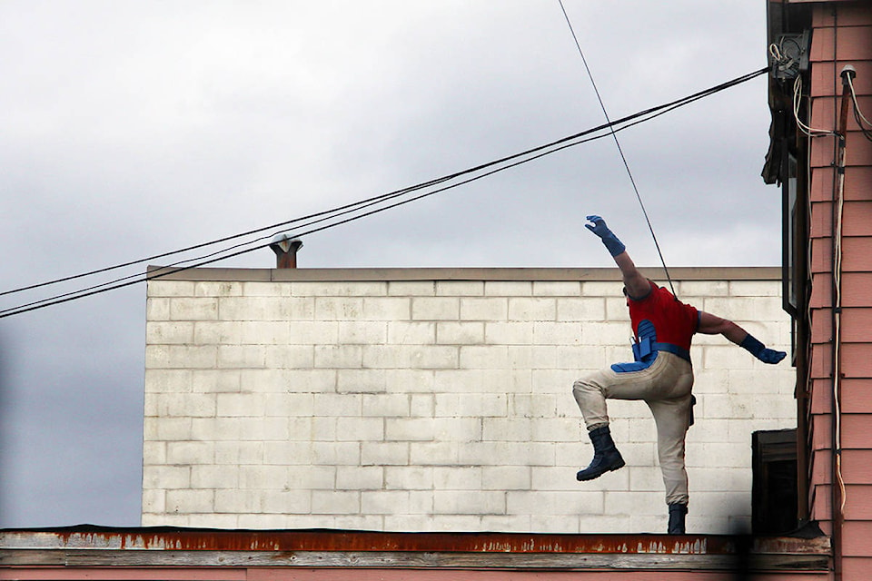 An unknown stuntman leaps out a window on the second of floor of the Dann’s Electronics building in Cloverdale March 19. (Photo: Malin Jordan)