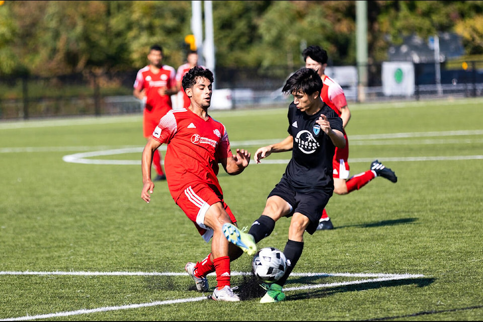 Savic Vellios (left, in red), with Surrey United’s U17 boys team, battles with a Fusion FC opponent during a 2-0 win for United at Cloverdale Athletic Park on Saturday, Oct. 1, 2022. (Photo: Anna Burns)