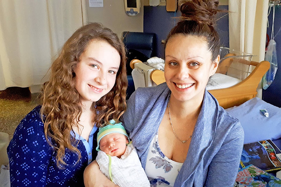 Meldrum Creek residents Bailey Stowell, 13, (left) and her mom, Liz Verges, cuddle up with baby Tijmen who was born in the front seat of a car while travelling down the Sheep Creek Hill en route to the hospital in Williams Lake. Monica Lamb-Yorski photo