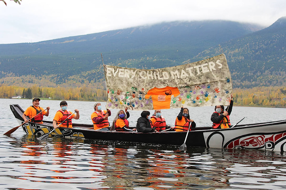 Staff of the Dze L K’ant Friendship Centre hold up a banner honouring residential school survivors on Lake Kathlyn for Orange Shirt Day, Sept. 30. (Thom Barker photo)