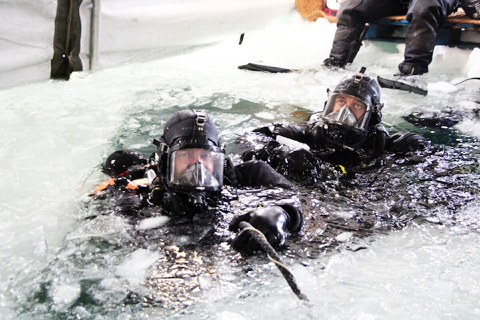 Sailor First Class William Henderson, of the Royal Canadian Navy, prepares to dive under the ice of Sheridan Lake with a member of the Royal New Zealand Royal Navy last week. The navy ran a five-day exercise with members of the United States Navy, NZRN, the Royal Navy and the Netherlands Royal Navy. (Patrick Davies photo - 100 Mile Free Press)