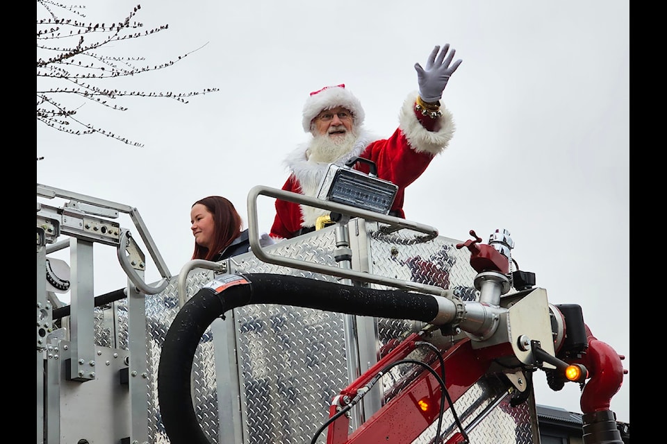 Santa Claus waves to the crowds at the 2024 Comox Valley Holiday Parade along 5th Street. 