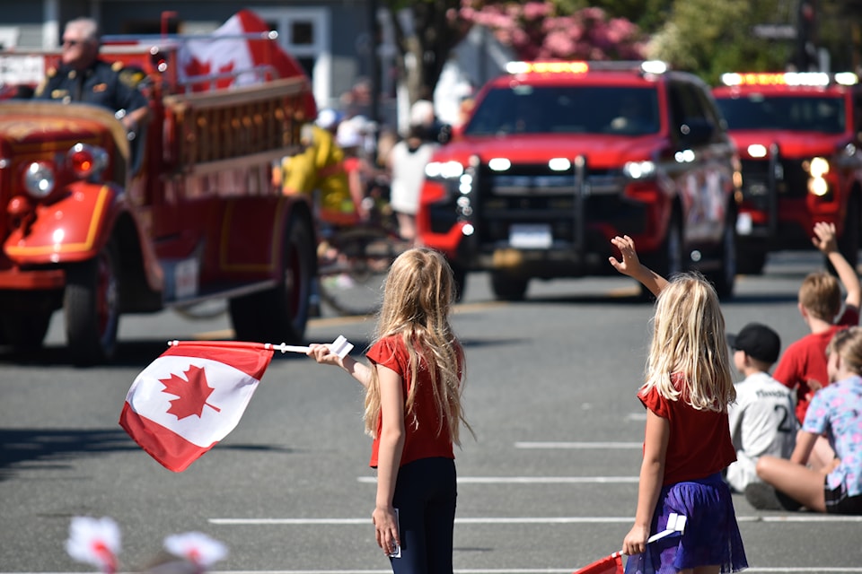 Two girls wave their flag as firetrucks make their way down Fifth Street.