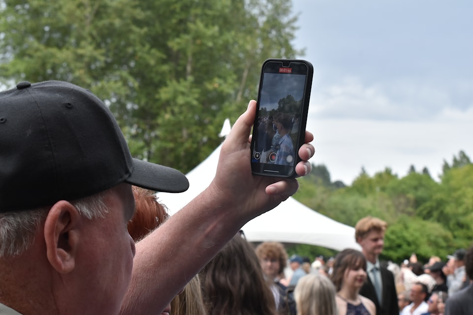 A high-angle phone capture from the audience as grads walk into the ceremony. 