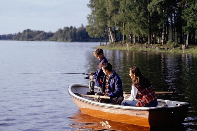 Family with one child (8-9) fishing in boat in lake