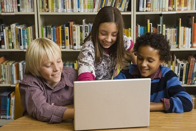 Children in library with laptop computer