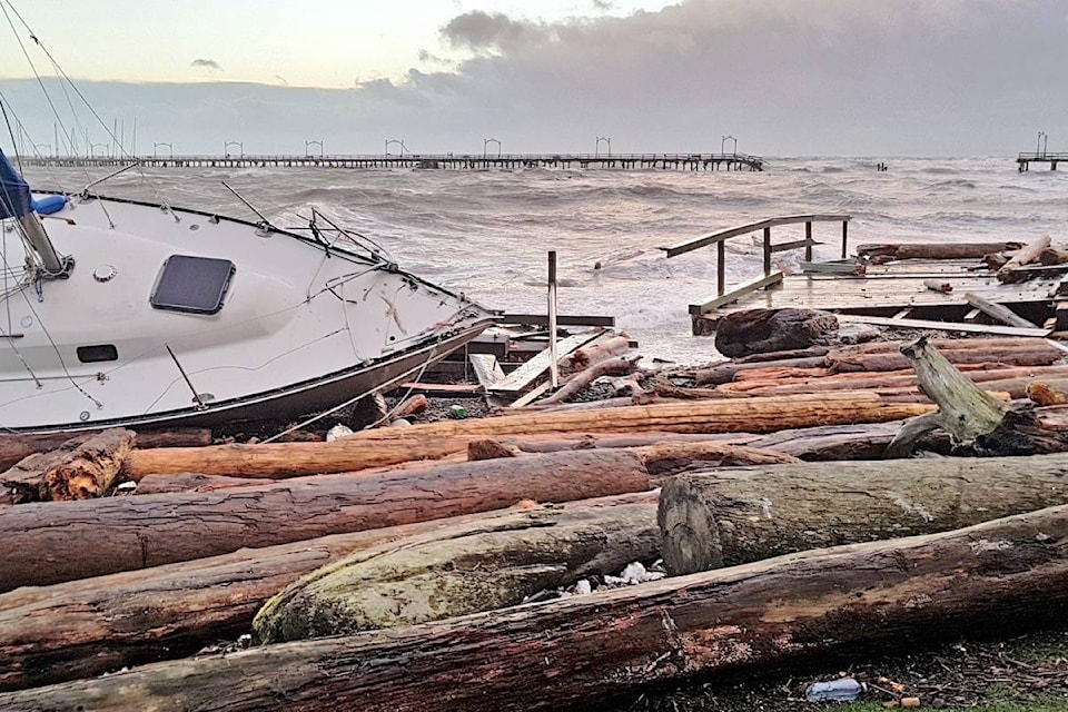 A shattered sailboat and remnants of the pier rest near the white rock, backdropped by the broken structure. (Christy Fox photo)