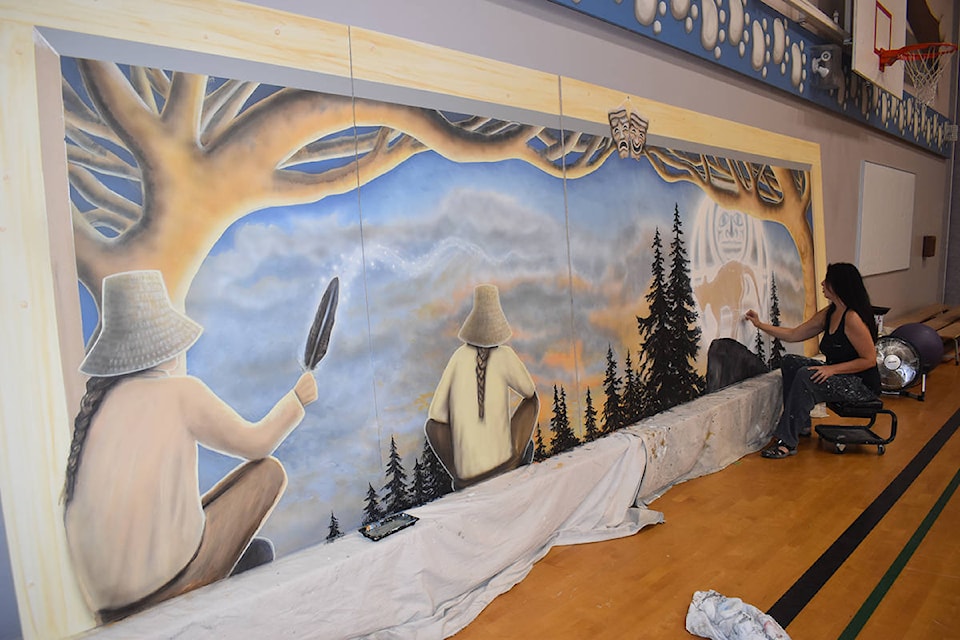 Kelly Everill puts the finishing touches on one of two new murals for Lake Trail Middle School. Photo by Terry Farrell