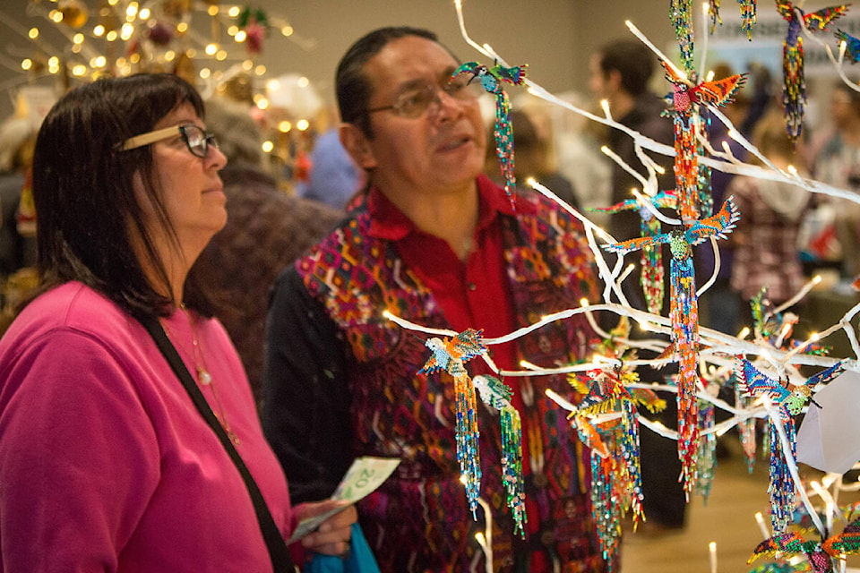 Julio Cochoy of Guatemala is showing an admiring customer the beautiful beaded hummingbirds crafted by women in his Guatemalan village. Photo supplied