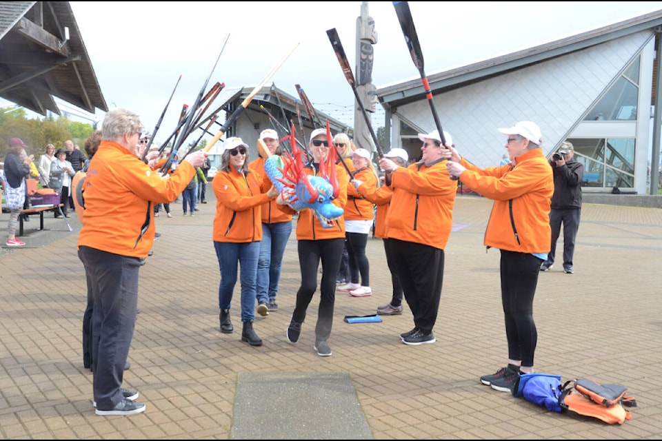 Under a paddle arch, the Hope Afloat team brings the dragon’s head to the boat on Saturday. Photo by Mike Chouinard