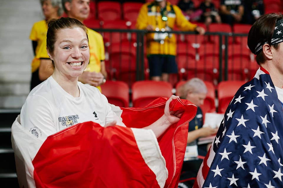 Emilie Poulin is draped in the Canadian flag after her powerlifting performance at the 2022 Invictus Games. Photo by Lyndon Goveas, Canadian Forces Morale and Welfare Services