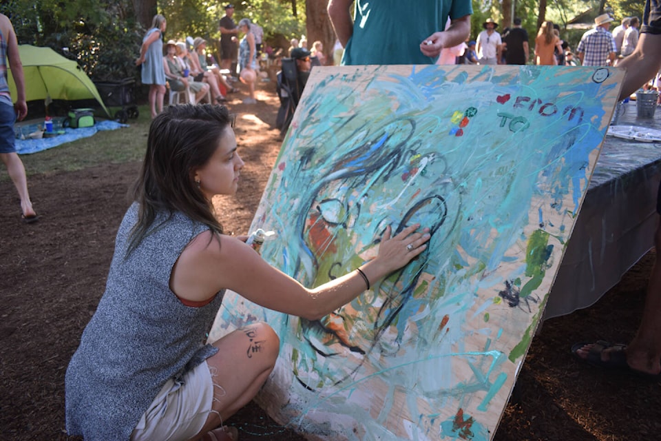 Samantha Bishop adds her contribution to the community painting set up at the Filberg Festival. Photo by Terry Farrell