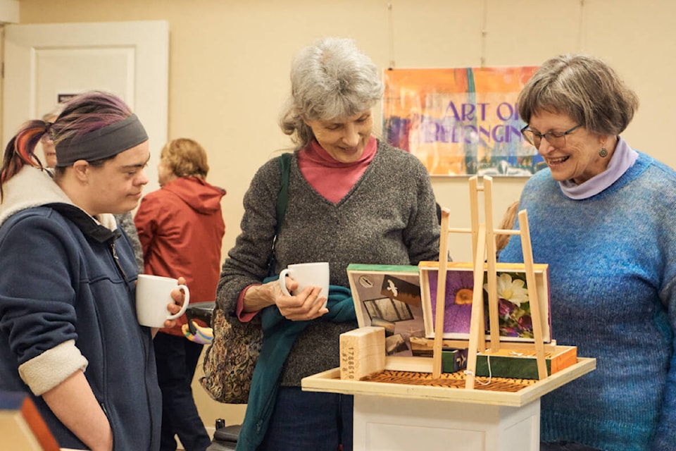 Hollee Card (community leader for L’Arche Comox Valley - right) and Noella Rousseau (artist - left) with her aunt Irene, enjoy some of the art exhibited at the Art of Belonging celebration.