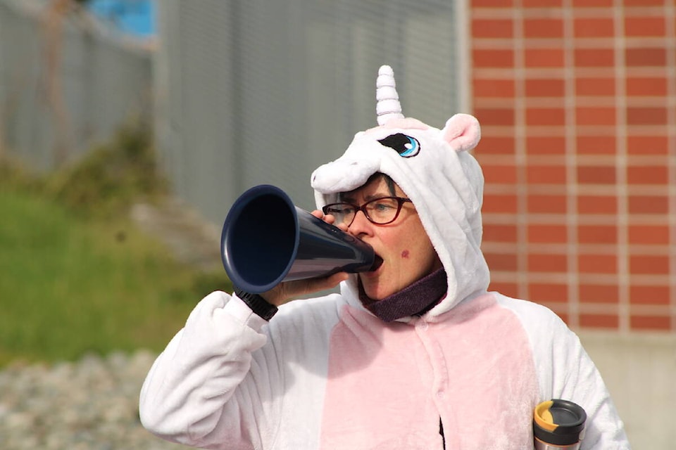 A unicorn-costume-clad striker carrying a sign reading “fair pay is no fantasy” was one of the many federal civilian workers involved in CFB Esquimalt operations picketed outside the Greater Victoria naval base on April 19 as nationwide strike actions followed a missed deadline for a new deal to be struck. (Jake Romphf/News Staff)