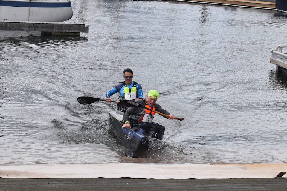 Ron Williams jumps out of the canoe at the Comox Marina as Rupurt Wong keeps it steady. Williams then ran up the dock and rang the bell to make Tsunami’s win official. It was their first victory since 2017. Photo by Terry Farrell