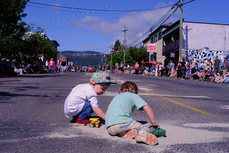 Two kids are playing with their toy trucks on Dunsmuir Avenue before the Victoria Day Parade in Cumberland. (Olivier Laurin / Comox Valley Record)