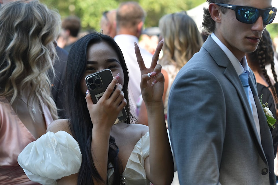 A grad poses for the camera as she records the moment on her phone. Photo by Erin Haluschak/Black Press