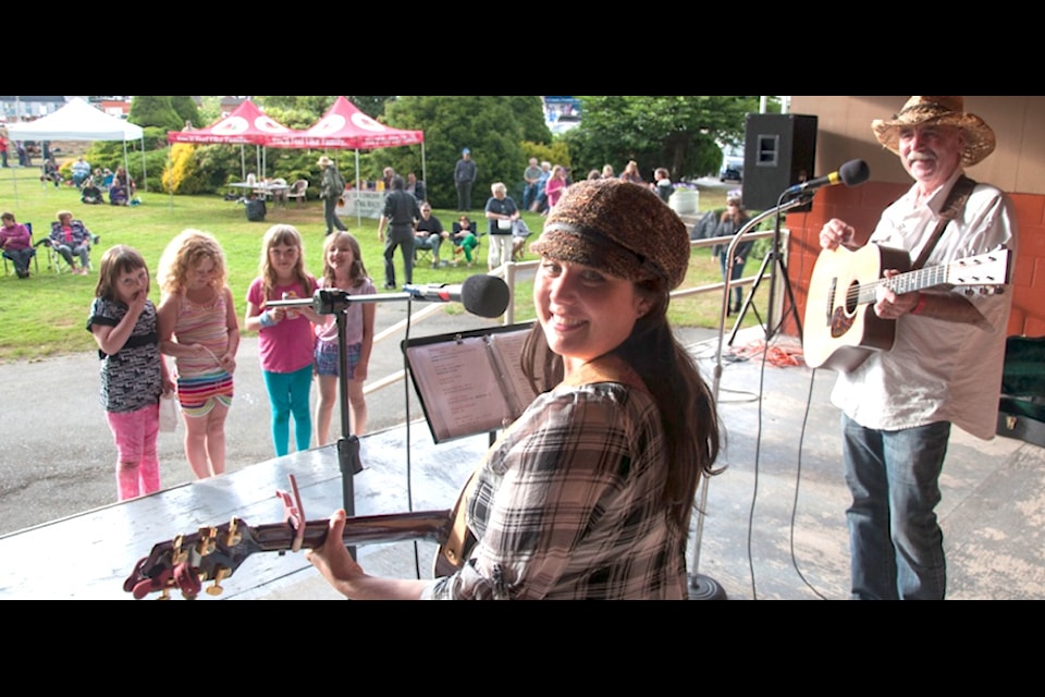 "Hometown singer Mary Egan, alongside friend Ron Ingram, performs for the crowd and young fans Melissa Bell, Megan Bell, Savanna Virosh and Esabelle Virosh at Central Park Saturday evening."