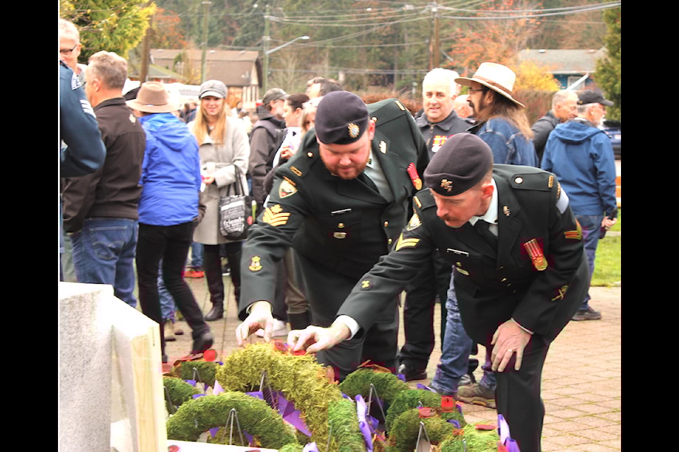 Members of the Canadian military pin poppies on one of the wreaths at the cenotaph following the service.