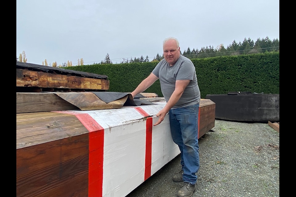 Bart Robertson owner of Maxwell's Auto Service and Genuine Collectibles poses in front of the a a sectioin of the world's largest hockey stick that once called the outside of the Cowichan Valley Community Centre its home.