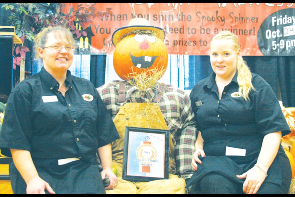"Janice Shand, left, and Megan Scammell, right, sit with Big Country, who was part of the Country Grocer’s booth display at the Chamber of Commerce’s Community Connections business showcase last Saturday. The display, complete with straw man, pumpkins, bales and more, won the 2014 People’s Choice Award for this, the first annual showcase event. More than 300 people attended the event."