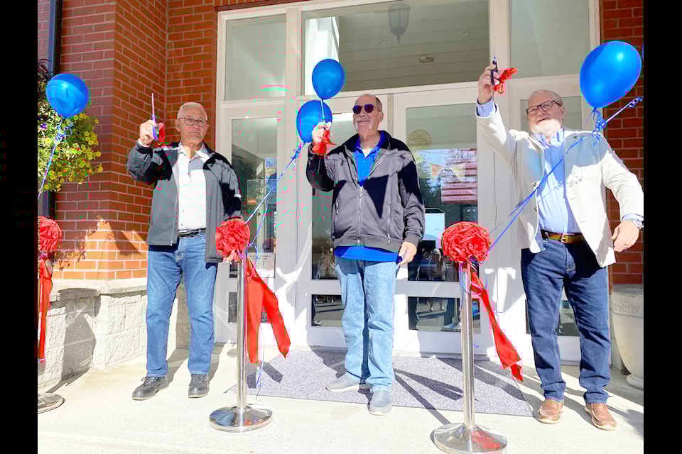 Arbutus Ridge council member Perry Mogus, left, vice-president Myles Anderson, and council member Edward Kozicki hold up the cut ribbon to celebrate the renovations made to their town hall.