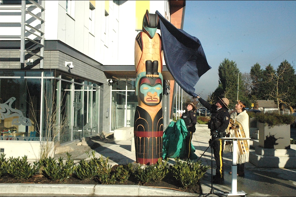 Coast Salish artist Dylan Thomas stands by while RCMP officers unveil the totem pole he carved during a ceremony at the new North Cowichan/Duncan RCMP detachment on Jan. 15. (Robert Barron/Citizen)
