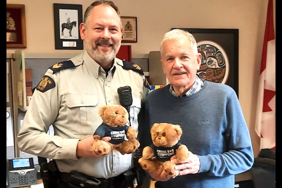 Sgt. Colin Cook, Shawnigan Lake detachment commander, and Brian Cornborough, president of Central Vancouver Island Crime Stoppers, hold two of the 25 Trauma Bears donated to the detachment.