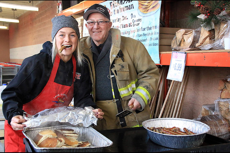 Lake Cowichan firefighters Elija Ellison and Doug Callsen are ready to hand out breakfast pancakes and sausages. (Lexi Bainas/Citizen)