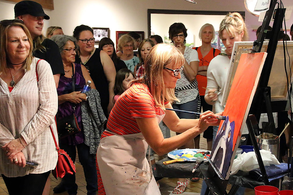 The crowd circles the room in the Arbutus Gallery, watching the Art Battle painters work. Here, we can see, in front, Pauline Dueck, and behind, Skye Skagfeld is at her easel. (Lexi Bainas/Citizen)