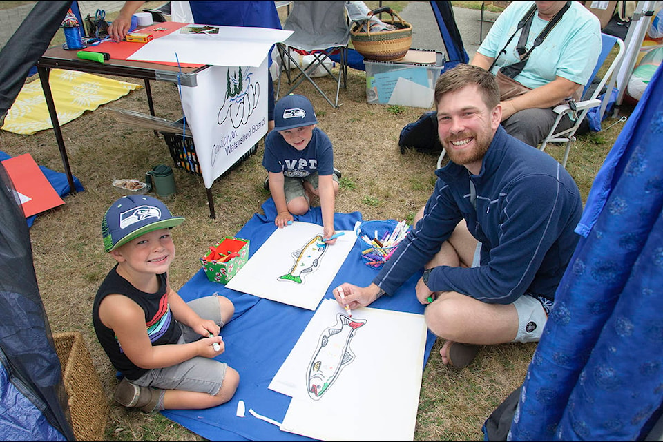 Brendan Morgan helps Kane and Maverick colour fish at the Watershed Board booth. (Malcolm Chalmers/Gazette)