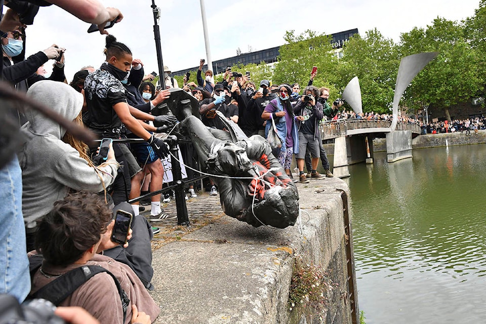 Protesters throw a statue of slave trader Edward Colston into Bristol harbour, during a Black Lives Matter protest rally, in Bristol, England, Sunday June 7, 2020, in response to the recent killing of George Floyd by police officers in Minneapolis, USA, that has led to protests in many countries and across the US. (Ben Birchall/PA via AP)