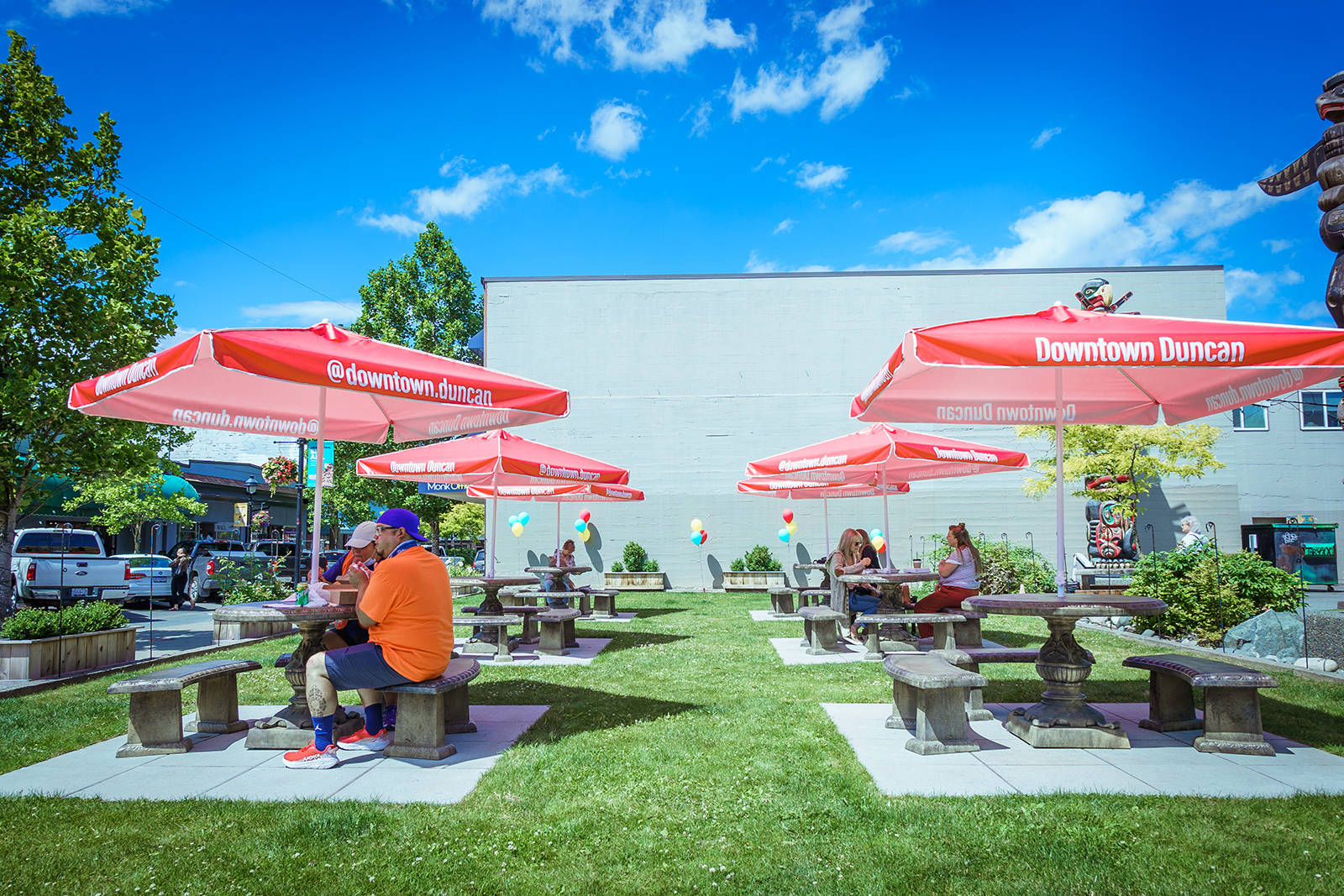 Six round concrete tables with benches and red umbrellas welcome guests in the park at 85 Station St., the perfect place to enjoy takeout from area restaurants and soak in the ambiance of downtown Duncan this summer. Two of the tables are designed to be wheelchair accessible. Photo by Keyworks Design