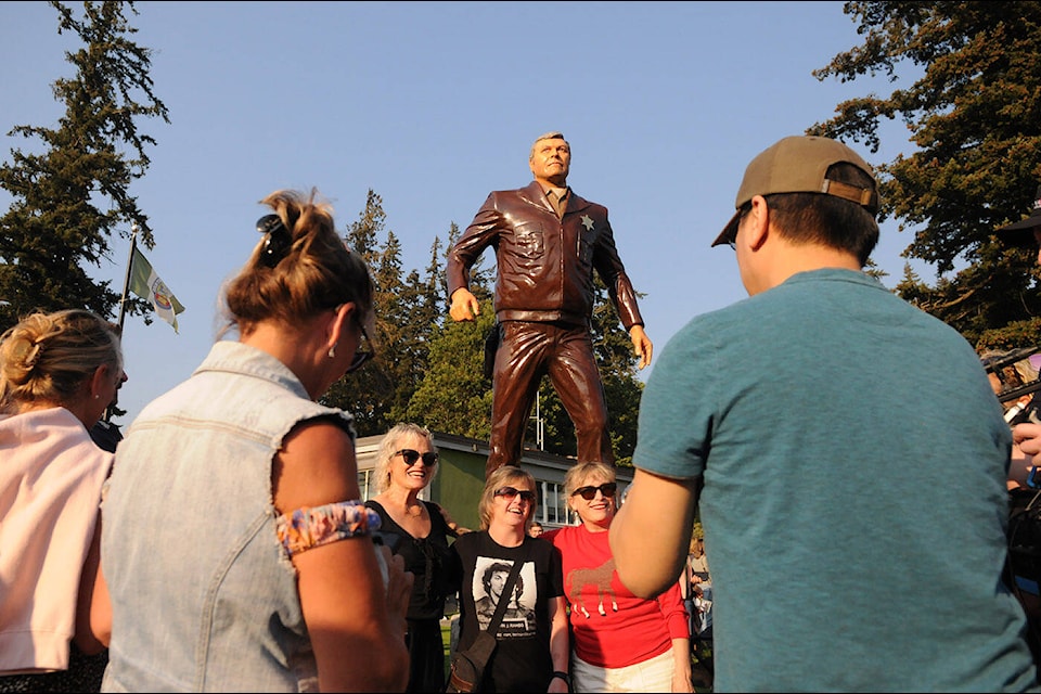 Elizabeth Dennehy (left) and Kathleen Dennehy (right) pose with a fan in front of the newly unveiled Sheriff Will Teasle carving (played by actor Brian Dennehy) during the Rambo First Blood 40th Anniversary celebrations in Hope on Saturday, Oct. 8, 2022. The Dennehys are the daughters of Brian Dennehy who starred in the 1982 film alongside Sylvester Stallone. (Jenna Hauck/ Black Press Media)