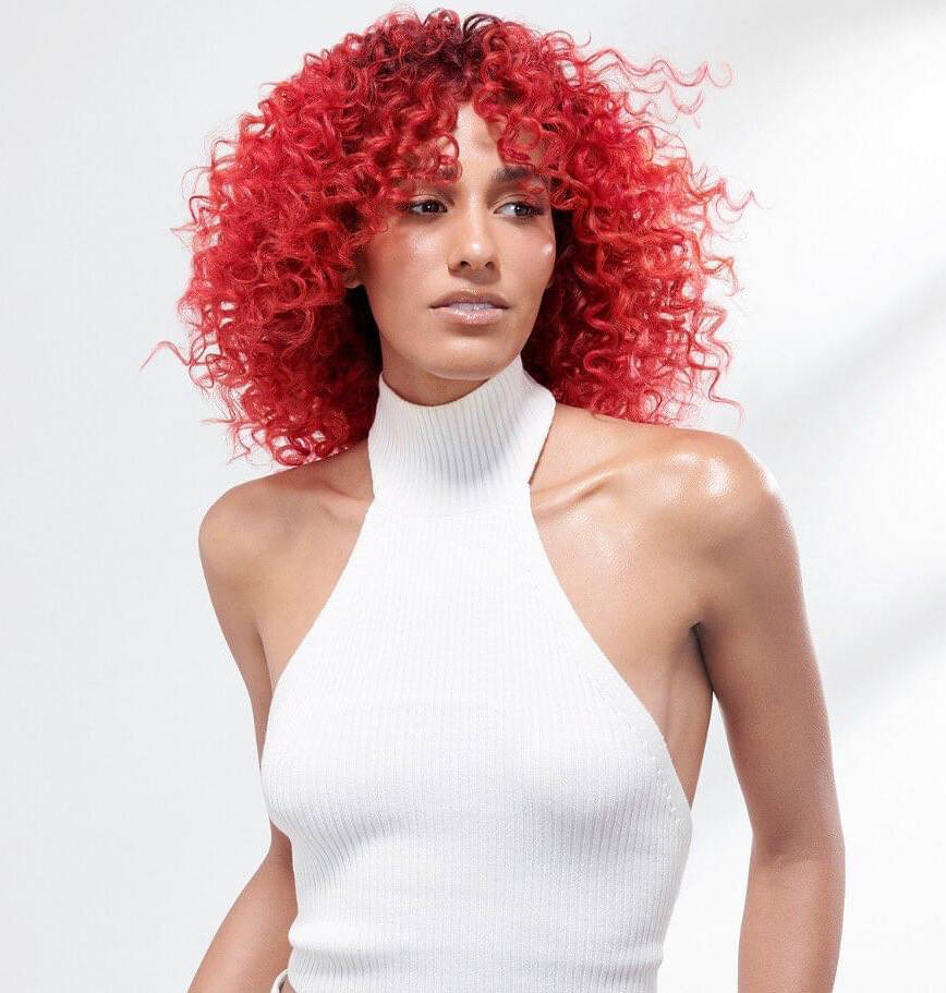 A vibrant red being shown off with stunning natural curls.