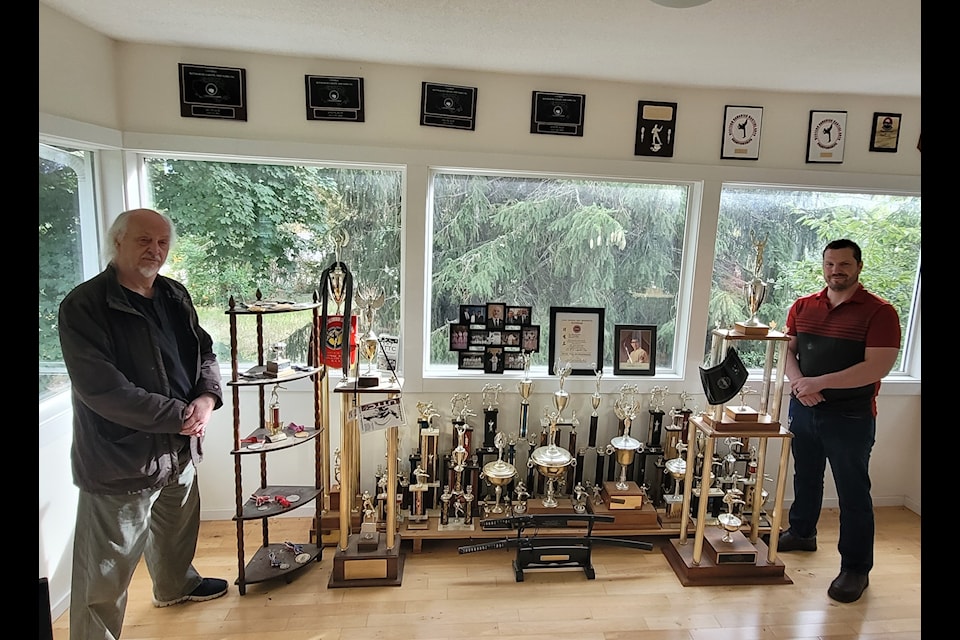 Tom Thurston poses with all of his competition trophies, alongside Derek Hall. 