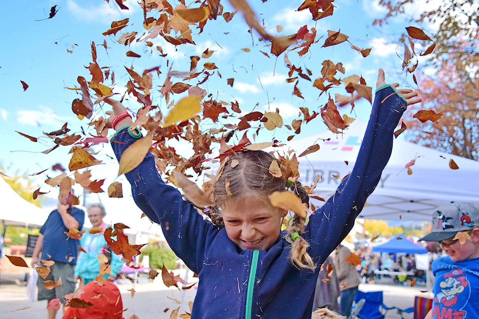 Selina Gysi lets an armful of leaves fly into the air in the leaf play area at Apple Fest on Saturday, Sept. 29. (Lachlan Labere/Salmon Arm Observer)