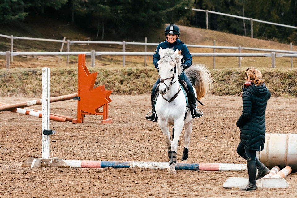 Becky Perkins, the owner of Woodcreek Equestrian clears an obstacle on her horse as instructor Maeve Drew looks on (Kayleigh Seibel/Salmon Arm Observer)