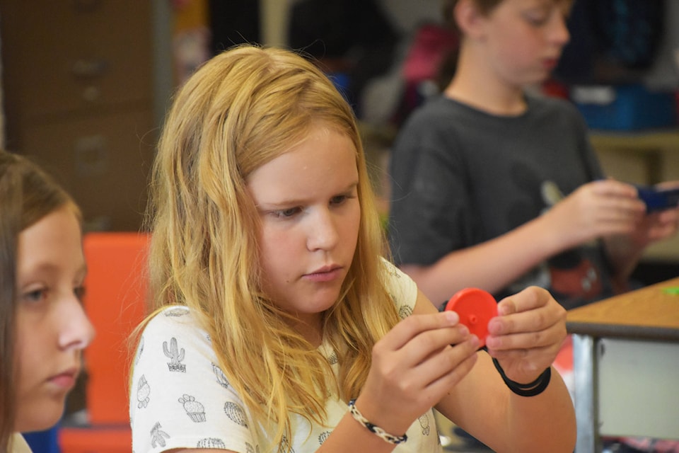 Jaylynn Anderson carefully puts a rubber ring on one of the wheels for her car at Hillcrest Elementary on Tuesday, June 11. (Cameron Thomson/Salmon Arm Observer)