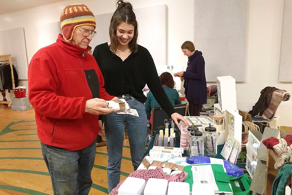 Thomas Preston looks over products from On Alex, Local and Global Boutique, with Jade Lutz of the Mirella Project during the Gifts Gone Green Christmas event on Dec. 6. (Martha Wickett/Salmon Arm Observer)