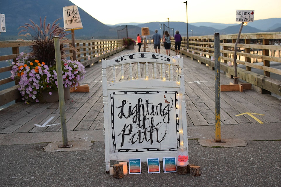 People take time on the evening of Sept. 10 to walk up and down the wharf at Marine Peace Park among the supportive signs and twinkling lights of the Walk the Wharf event put on to raise awareness of suicide prevention. (Martha Wickett - Salmon Arm Observer)