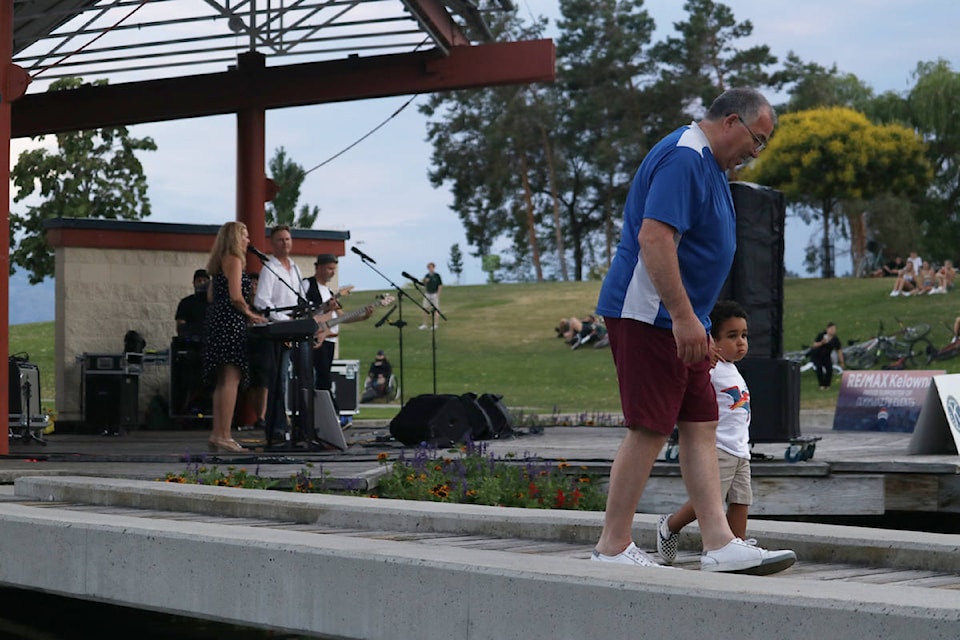 A man brings a child front and centre of Audience members cheer on Cover2Cover during the band’s performance at the Island Stage at Waterfront Park on July 7. (Aaron Hemens/Capital News)