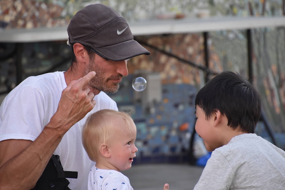 During the Gathering Together Festival on June 27 in Downtown Salmon Arm, Paul Lefebvre focuses on a big bubble hovering in front of his face, but his baby Luc is too enthralled with a new friend to notice. (Martha Wickett-Salmon Arm Observer)
