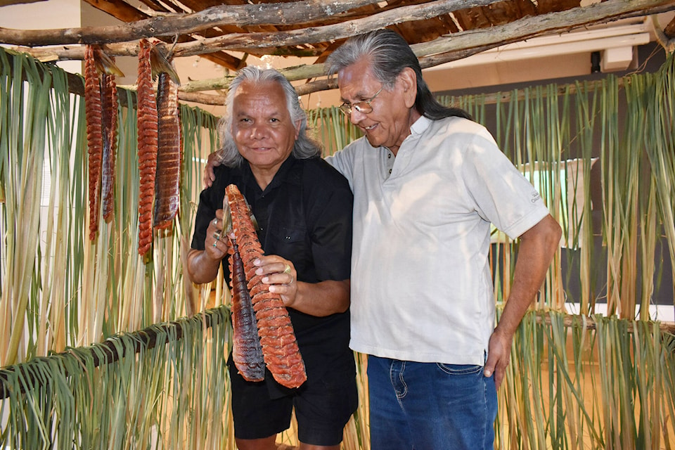 Gerry and Louis Thomas stand Aug. 27 with already-smoked salmon in the smokehouse they built in the Salmon Arm Arts Centre. Gerry spent a day with the Skeetchestn First Nation west of Kamloops in order to get the sockeye salmon to bring for the exhibition. (Martha Wickett - Salmon Arm Observer)