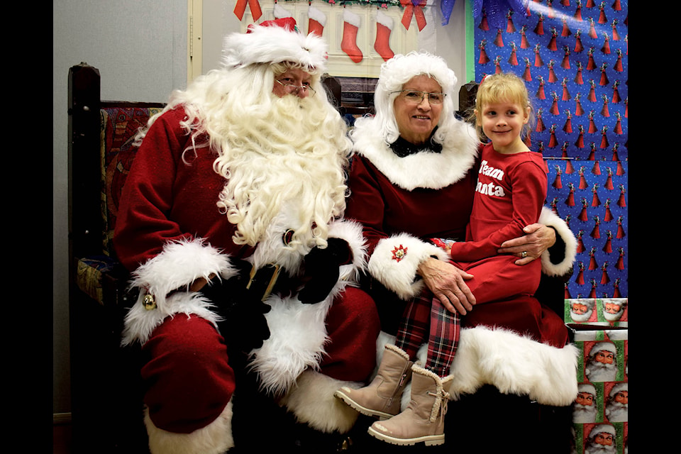 Macklyn Cairney, six, wears her “Team Santa” shirt as she smiles alongside Santa and Mrs. Claus in the Kids Zone at the Spirit of Sylvan Yuletide Festival and Market at the NexSource Centre on Nov. 30. Photos by Kaylyn Whibbs/Sylvan Lake News