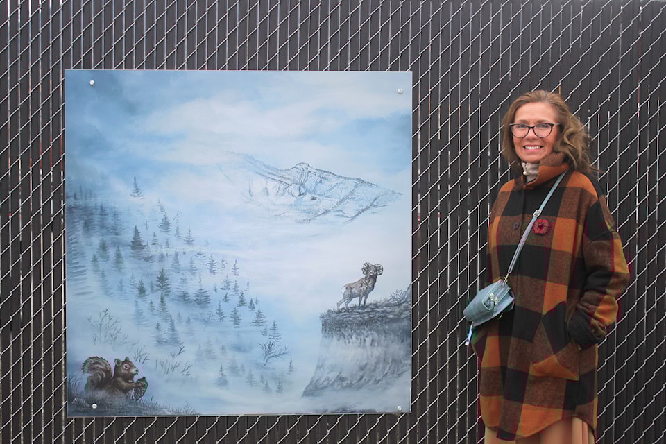 Erin O'Neil Gravelle stands beside a copy of her painting at an art unveiling in Fernie on Oct. 30. Gravelle's painting depicts a Ktunaxa story about a young boy who slays a bighorn sheep and a squirrel, in a quest to find wood for a bow and arrow (Gillian Francis/ The Free Press)