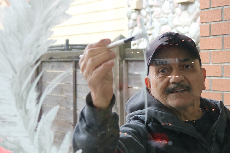 Shahab Rahmanian paints a winter wonderland scene in the windows of the Goldstream News Gazette.