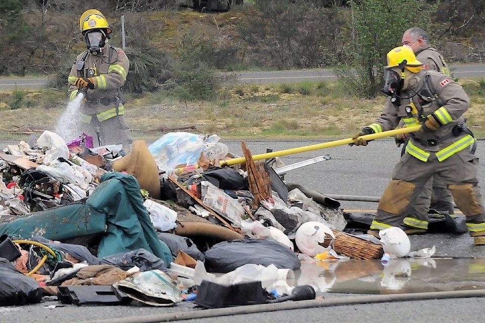 Nanoose Volunteer Fire Department firefighters hosed down a pile of garbage that was hauled out from a semi-trailer that caught fire at the Parksville weigh station on Tuesday, April 28. (Michael Briones photo)